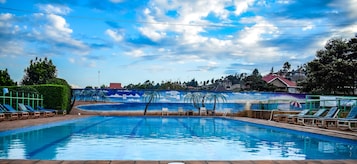A swimming pool with lounge chairs and a mural of palm trees.