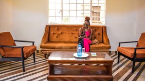A room with a sofa, two armchairs, a coffee table, and a window with a view. - Rio Breeze Gardens (Nairobi)