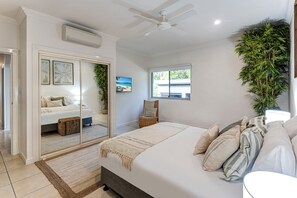 A bedroom with a bed, a ceiling fan, a window, and a plant. - Blue Water Views 17 (Hamilton Island)