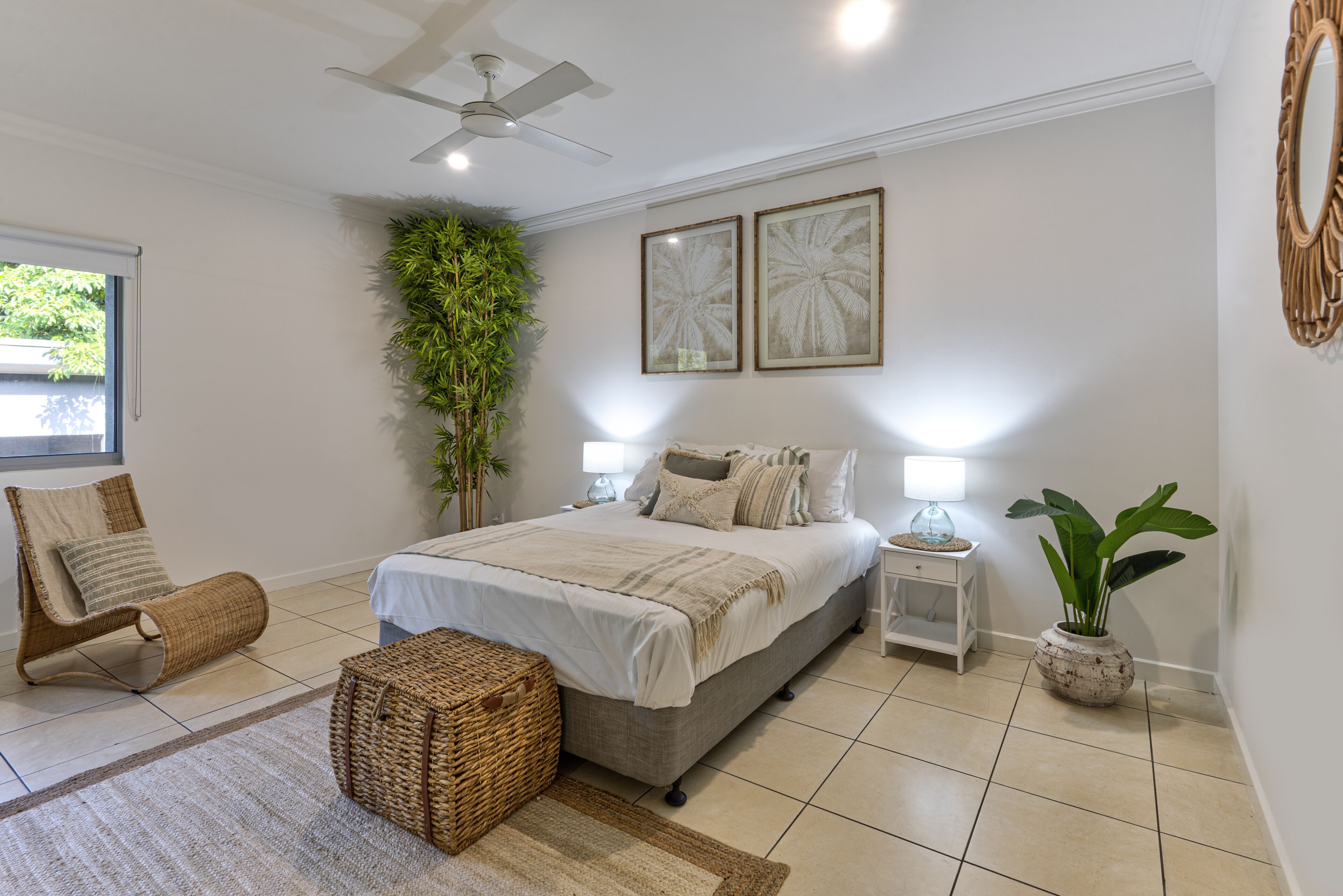 A bedroom with a bed, a chair, a nightstand, a lamp, and a potted plant.