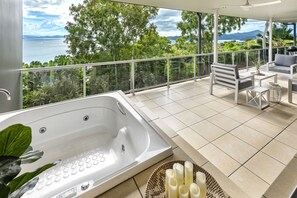 A balcony with a hot tub, seating area, and a view of the sea. - Blue Water Views 17 (Hamilton Island)