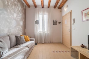 A room with a sofa, a wooden door, a lamp, and a window with curtains.