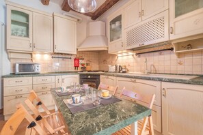 A kitchen with white cabinets, a marble countertop, and wooden chairs. - Casa Masa close to @S. Lucia Train Station (Venezia)