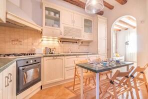 A kitchen with white cabinets, a stove, a dining table with chairs, and a window with a view.
