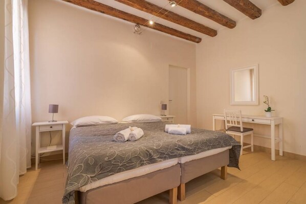 A bedroom with a bed, bedside tables, a desk, a chair, and a mirror.