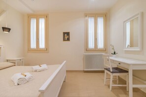 A bedroom with a bed, a desk, a chair, a radiator, and two windows. - Casa Masa close to @S. Lucia Train Station (Venezia)