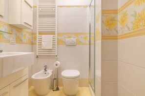 Ein Badezimmer mit Bidet, Toilette und einer Duschkabine aus Glas.