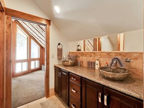 A bathroom with two sinks, wooden cabinets, a large mirror, and a view of a room with large windows. - Spacious mountain retreat • Built for gathering • Hot tub • Quiet setting • Minutes up Sundance Canyon (Sundance)