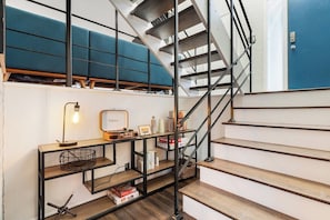 Eine Treppe mit Metallgeländer, Holzboden und einer blauen gepolsterten Sitzbank.
