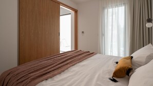 Quarto com cama, guarda-roupa de madeira e janela com cortinas.