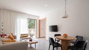 Uma sala de estar moderna com um sofá, mesa de centro e área de jantar com cadeiras e uma mesa.