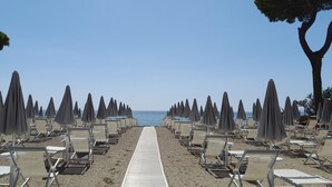 A beach with rows of sun loungers and umbrellas, a wooden walkway, and a clear view of the sea. - Hibiscus Beach Village - Family apartments within walking distance of the sea (Follonica)