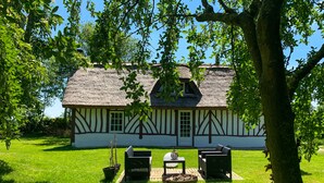 A traditional half-timbered house with a thatched roof, a grassy lawn, and outdoor seating. - Le Nid de Chaume, 15 min from Honfleur 4/6P Charming little cottage, (Martainville)