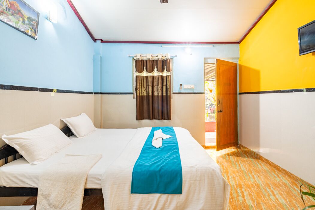 Une chambre d’hôtel avec un lit, une fenêtre avec des rideaux, une porte et une vue sur l’extérieur.