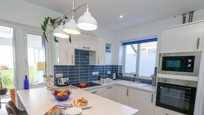 Eine moderne Küche mit weißen Schränken, einer zentralen Kochinsel mit Obstschale, einem Toaster und einem Wasserkocher.