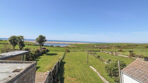 Ländliche Landschaft mit blauem Himmel, einem fernen Strand und einem eingezäunten Grundstück mit einem Weg.