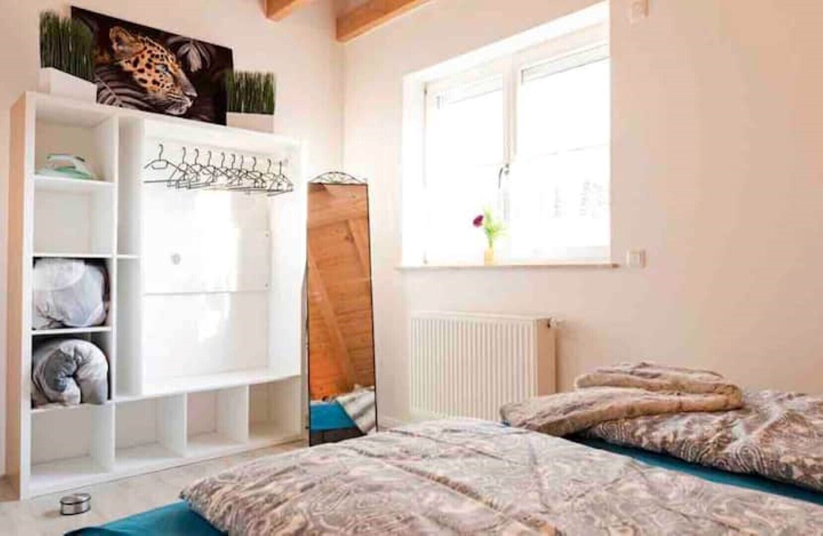 A bedroom with a bed, a wardrobe, a radiator, and a window with a view.