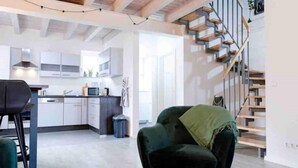 Un intérieur moderne comprenant une cuisine, un coin repas et un escalier.