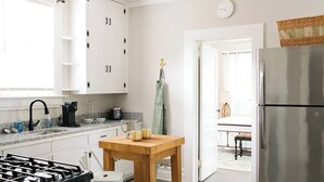 Una cucina moderna con mobili bianchi, un frigorifero in acciaio inossidabile, un tavolo di legno con due tazze gialle e una macchina da caffè sul bancone.
