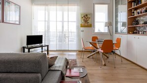 A modern living room with a sofa, a flat-screen TV, and a dining area with a table and chairs. - Una Terrazza Sulla Citt by Wonderful Italy (Bologna)