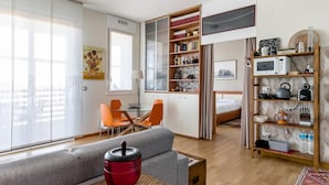 A compact living space with a sofa, a dining table with chairs, a kitchenette, and a bookshelf. - Una Terrazza Sulla Citt by Wonderful Italy (Bologna)