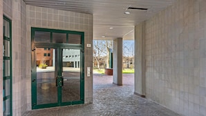 A covered walkway with a tiled floor and a green-framed glass door leading to a building. - Una Terrazza Sulla Citt by Wonderful Italy (Bologna)