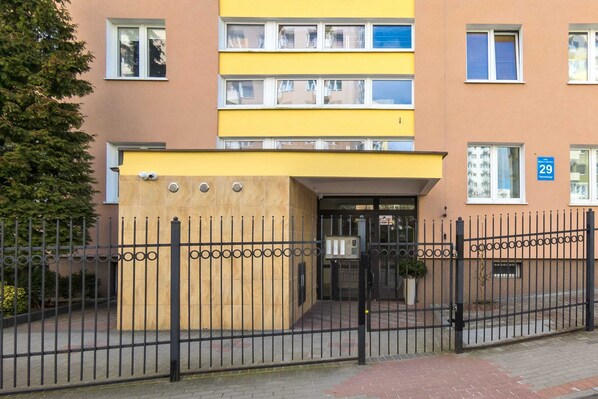 Un edificio de varios pisos con fachada amarilla y rejas metálicas negras.