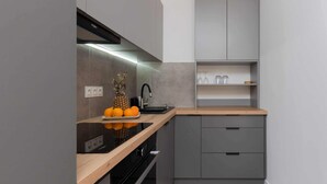 Una cocina moderna con armarios grises, encimera de madera y horno empotrado.