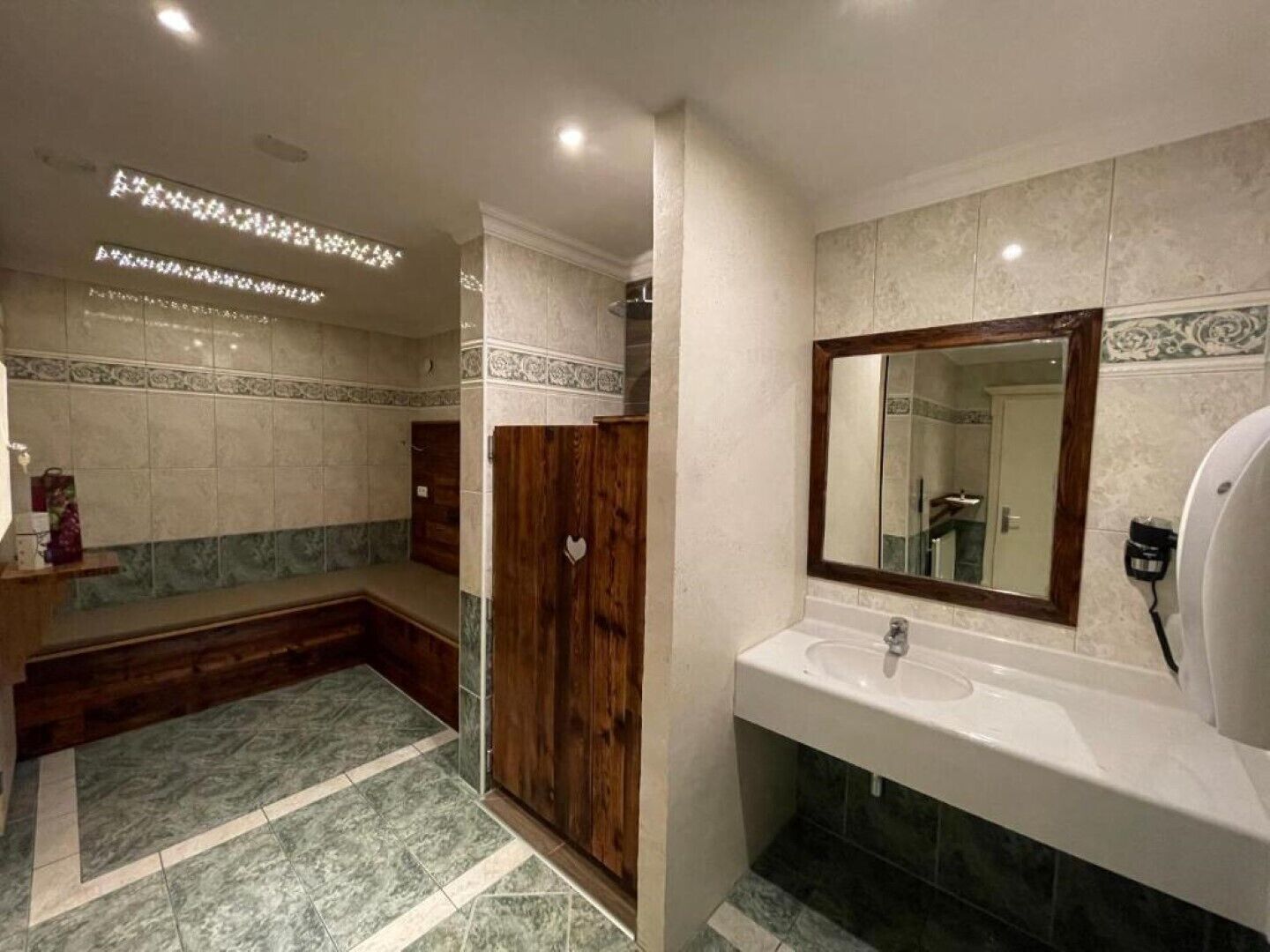 A bathroom with a wooden bench, a sink, and a mirror.