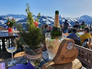 A table with a bottle of champagne, a glass of wine, and a wooden sign with the word "Reservation". - Family studio with a balcony - The ultimate active mountain resort (Kirchberg in Tirol)
