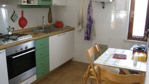 Una cocina con estufa, pileta y sillas de madera.
