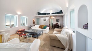 A spacious living area with a high ceiling, white walls, and a mezzanine level.