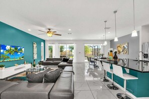 Un salon moderne avec un canapé, un téléviseur et un ventilateur de plafond.