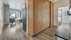 A modern kitchen with wooden cabinetry, a dining area with chairs, and a large window providing a view of the outside.