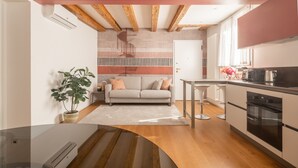 A modern kitchen with wooden beams, a dining area with a sofa, and a small table.
