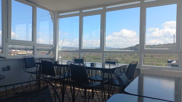Ein Essbereich mit Tisch und Stühlen, große Fenster mit Blick auf die Landschaft.