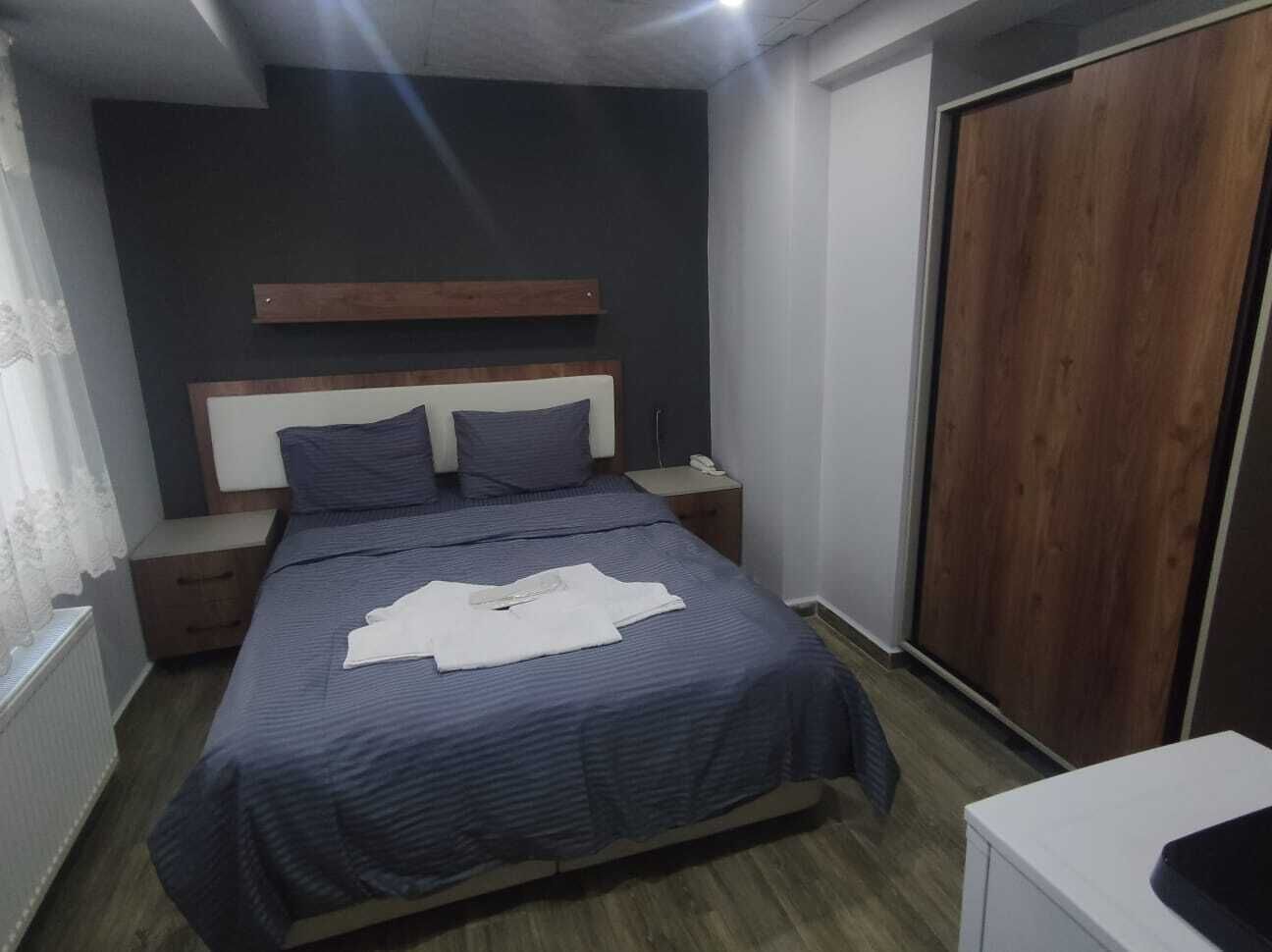 A bedroom with a bed, bedside tables, a wardrobe, and a radiator.