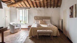 A bedroom with a large bed, a bench, a chair, and a window with a view. - Il Borghetto - The House of Elba, rooftop panoramic terrace (Castelnuovo dell'Abate)