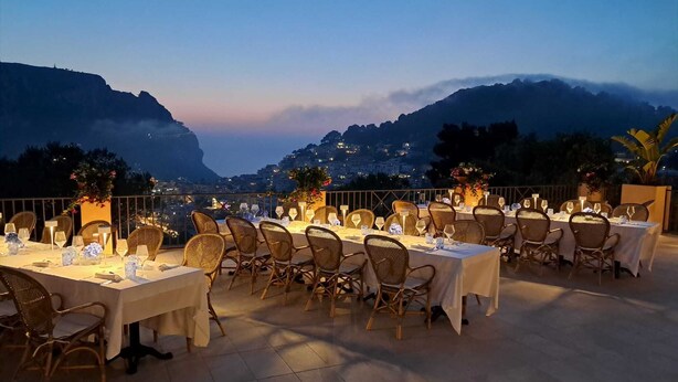 Un área de comedor en la azotea con mesas dispuestas para la cena, con vistas a un paisaje montañoso.
