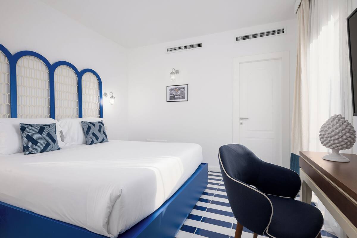Une chambre d’hôtel avec un lit, une chaise, un bureau et une porte.