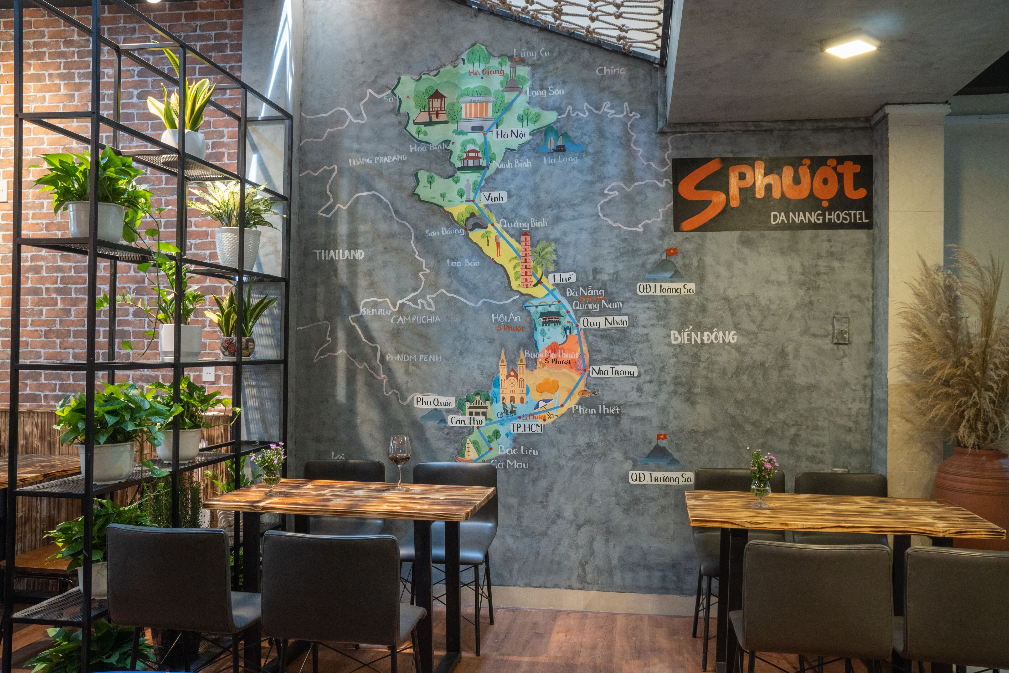 A dining area with tables and chairs, a map on the wall, and potted plants.