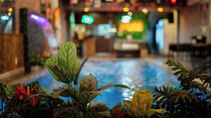 A pool area with tropical plants in the foreground. - S Phuot Da Nang Hostel (Da Nang)