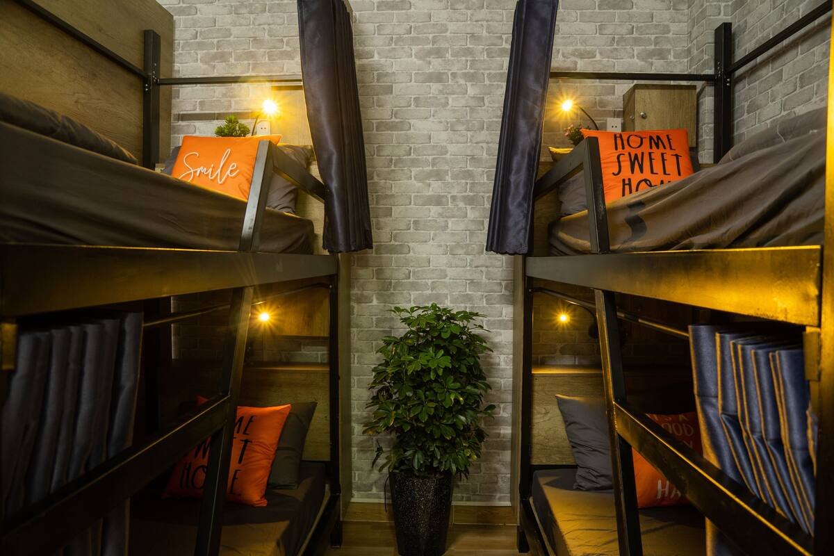 A room with bunk beds, a potted plant, and a sign that says "HOME SWEET HOME".