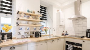 A modern kitchen with white cabinets, a wooden countertop, a built-in oven, and a stainless steel range hood. - The Nook (Criccieth)