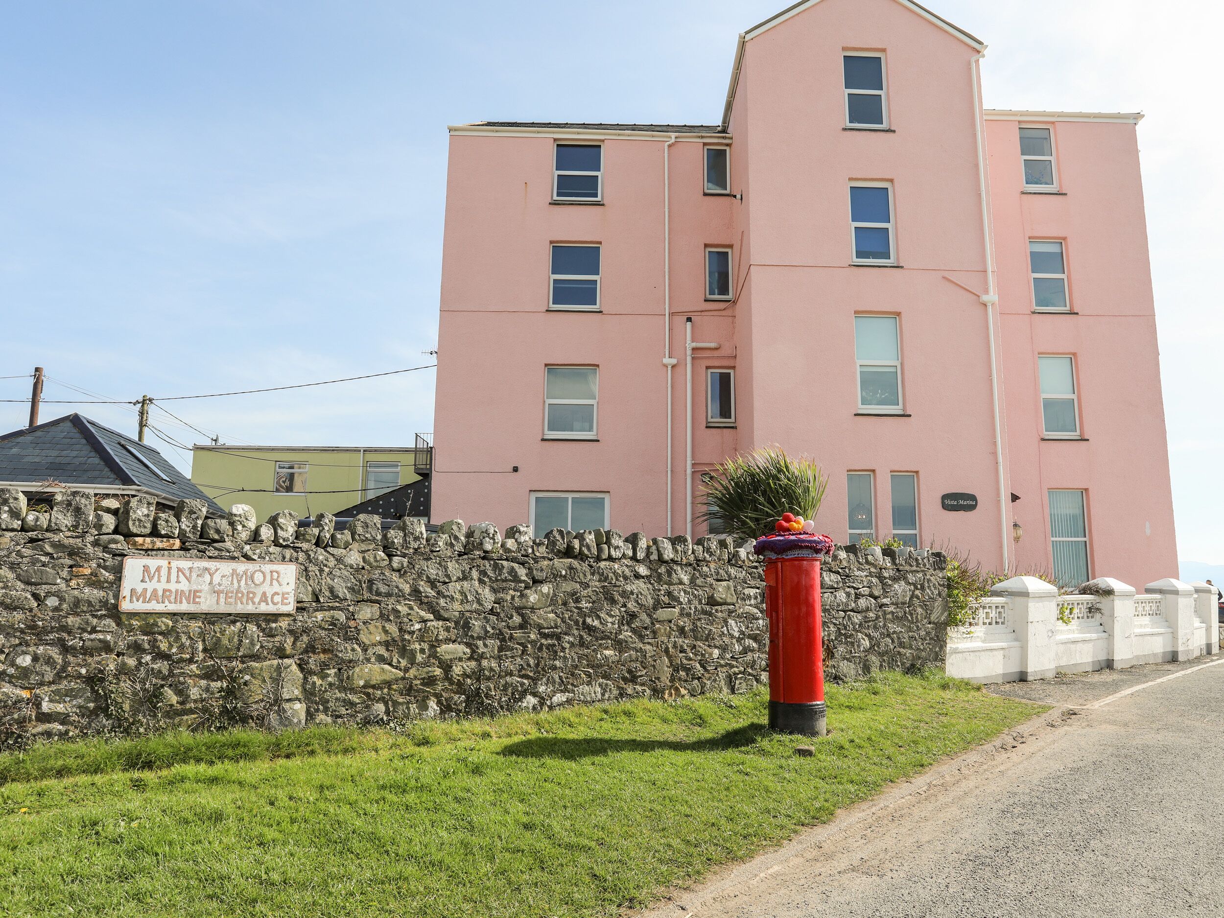 A pink building with a stone wall and a sign that reads 'MINY MOR. MARINE TERRACE.'