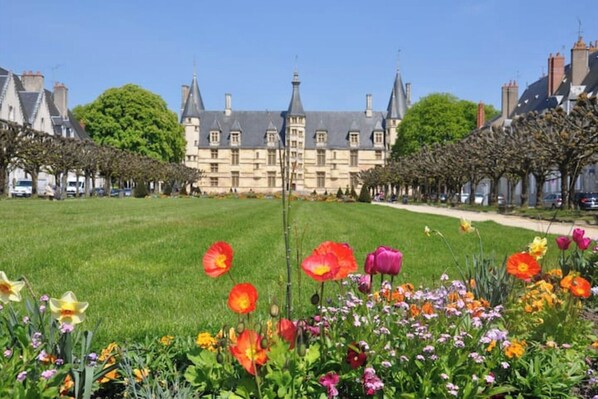 Relax in a serene garden surrounded by blooming flowers and a historic building with a prominent tower.