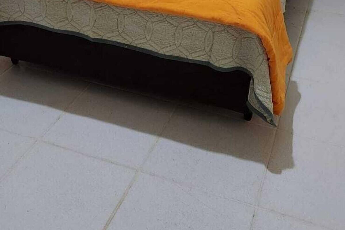 Una cama individual con una colcha estampada y un ventanal en la habitación.