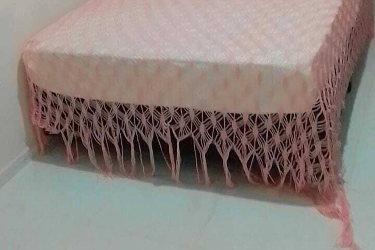 Una cama con una colcha rosa y un fleco decorativo.
