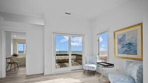 Un salon spacieux avec vue sur la plage, un coin repas et un tableau accroché au mur.