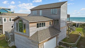 Une maison en bois à deux étages, dotée d’un garage, d’un balcon et d’un escalier menant à l’étage supérieur.